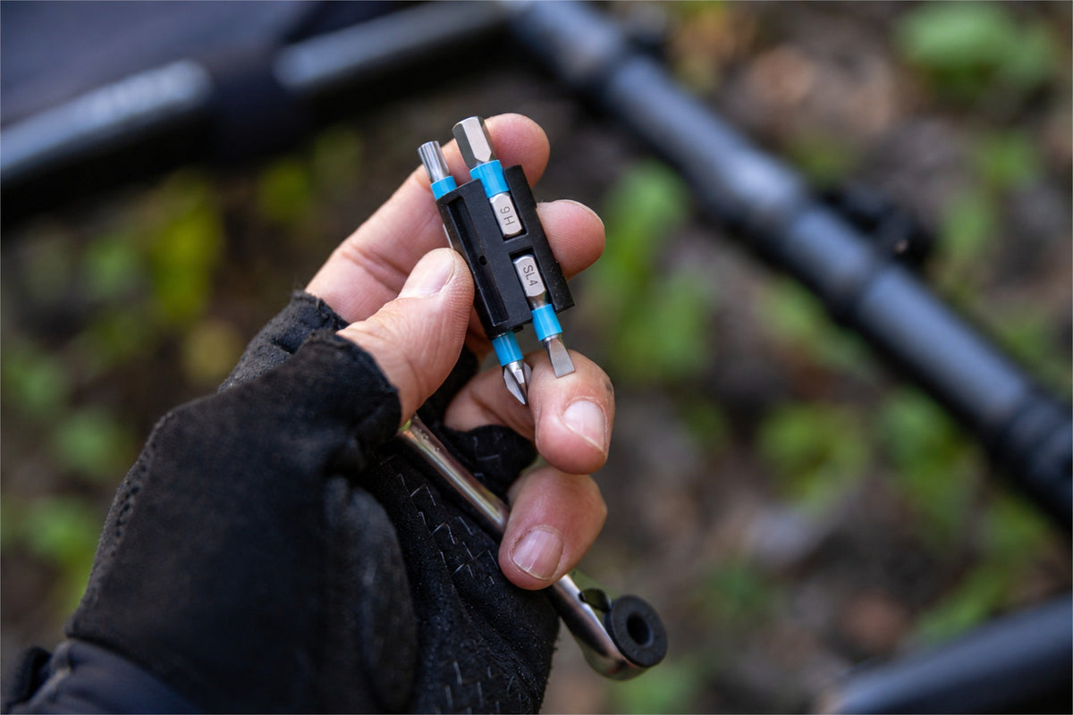 Compact multi-tool held beside a bicycle wheel for an on-ride repair kit