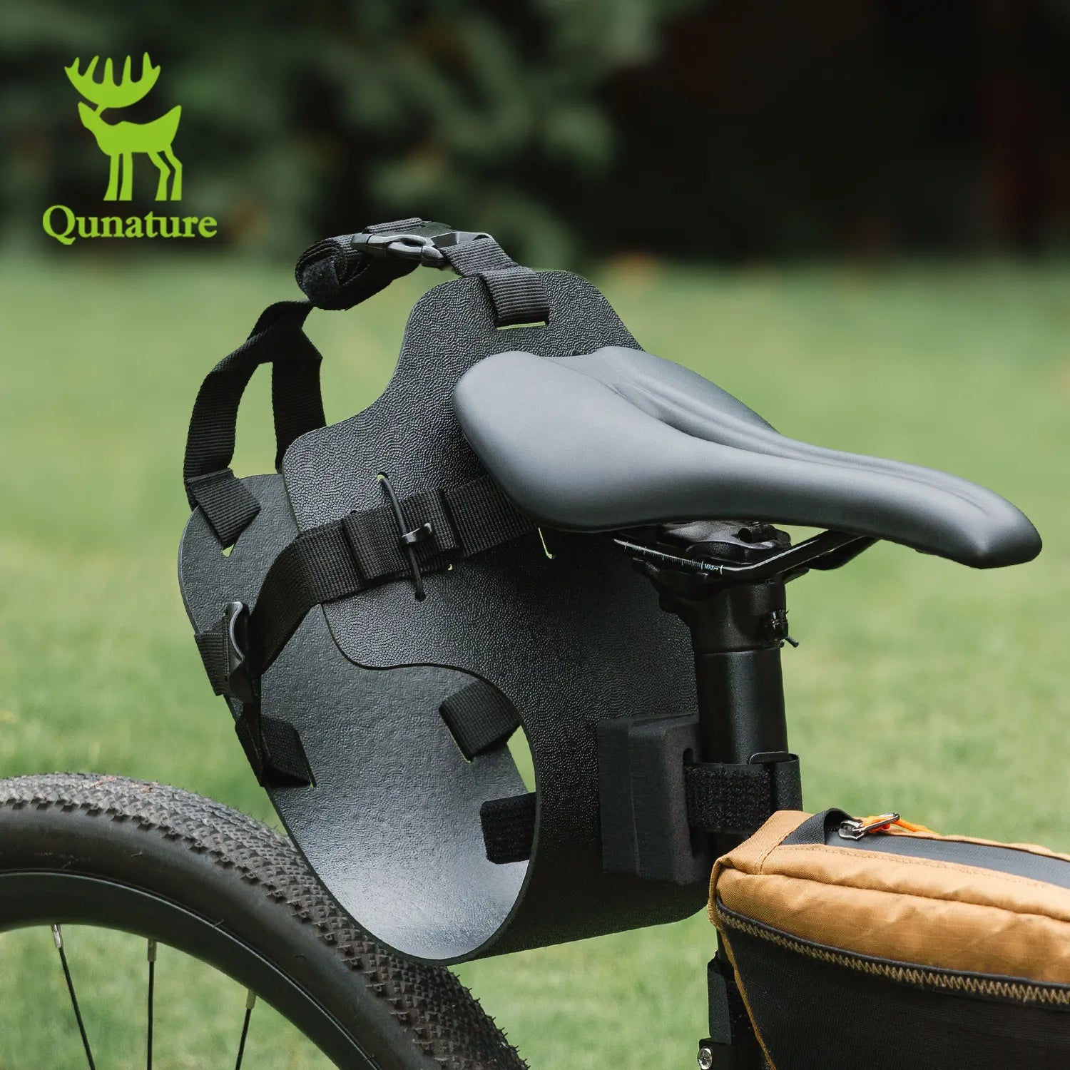 The black rear bag extension bracket is installed behind the bicycle seat outdoors on the grass