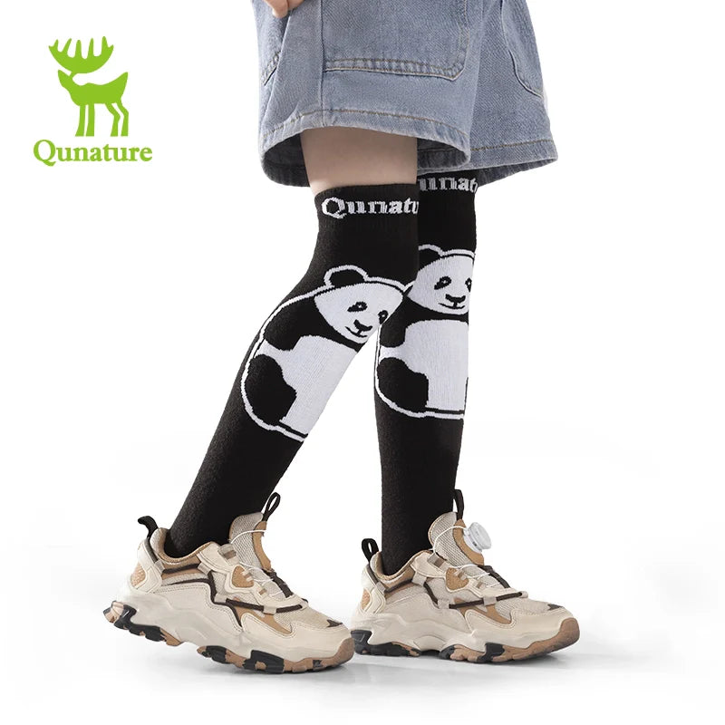 Person wearing black socks with panda designs and beige sneakers on a white background, with Qunature logo.