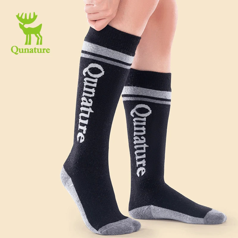 A person wearing a pair of black wool blend children's ski socks with thick fine terry lining