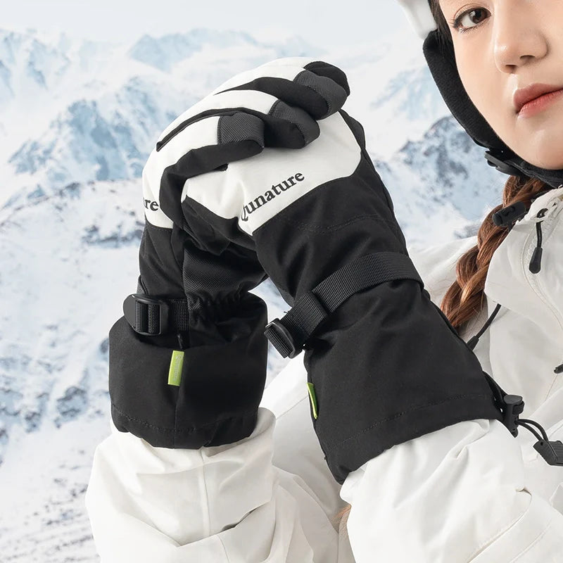 Person wearing black and white gloves with 'Qunature' text, standing against a snowy mountain background.