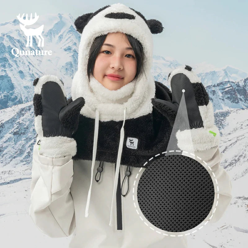 A girl wearing a pair of panda-shaped ski gloves smiles in the snow