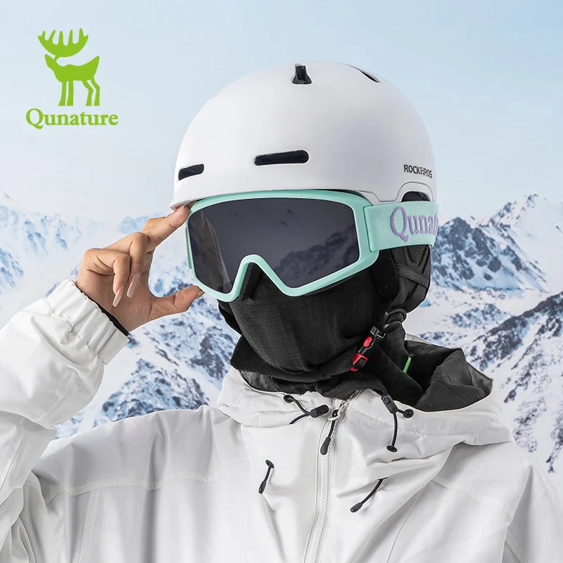 Person wearing a white helmet with goggles and a Qunature branded jacket against a snowy mountain background.